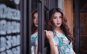 Длинноволосая девушка азиатка стоит у окна