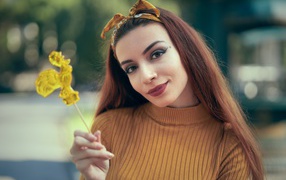 Длинноволосая девушка в свитере с леденцом в руке