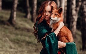 Рыжеволосая девушка в зеленом платье с лисой в руках 