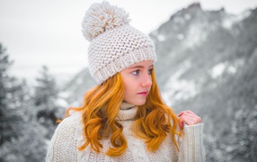 Рыжеволосая девушка в теплой шапке зимой 