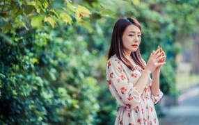 Грустная девушка азиатка в платье в парке