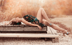 Стройная длинноногая девушка лежит на деревянном мосту