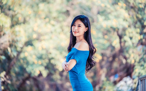 Улыбающаяся девушка азиатка в голубом платье 