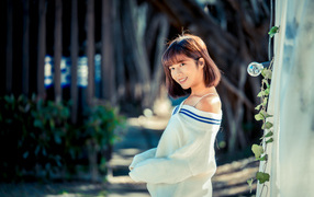 Улыбающаяся девушка азиатка в белом свитере 