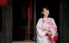Улыбающаяся девушка азиатка в кимоно с веером в руке
