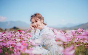 Улыбающаяся девушка азиатка на поле с цветами космеи 