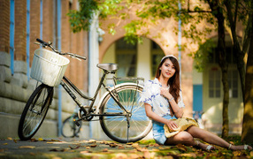 Улыбающаяся девушка азиатка с велосипедом в парке осенью