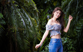 Улыбающаяся азиатка на фоне зеленых листьев