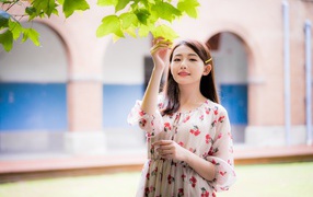 Улыбающаяся девушка в платье у дерева 