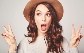 Surprised girl with long hair in a brown hat.