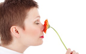 Женщина с закрытыми глазами с цветком герберы в руке