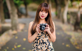 Молодая девушка азиатка с фотоаппаратом в руках 