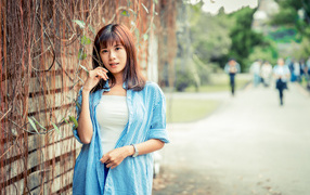 Молодая азиатка в рубашке у стены