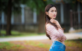 Молодая азиатка с длинными волосами в синих джинсах