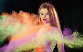 Молодая девушка в пыли от разноцветной краски 