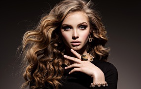 Молодая девушка в черном свитере с дорогими украшениями