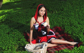 Молодая девушка в костюме сидит на траве, косплей