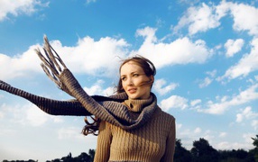 Молодая девушка в свитере на фоне неба
