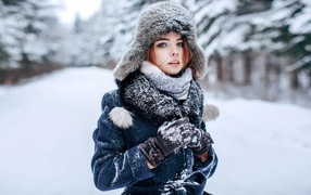 Молодая девушка в теплой шапке в зимнем лесу