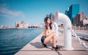 Молодая девушка в шортах сидит на пирсе