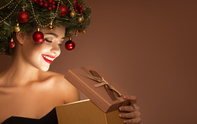 Красивая девушка с рождественским венком на голове с подарком