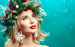 Beautiful girl with a wreath of fir branches on her head on a blue background