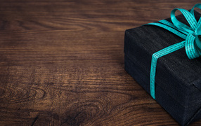 Подарок с синим бантом на деревянном столе 