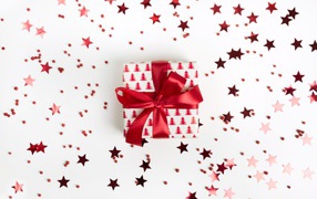 Подарок с красным бантом на белом фоне со звездочками