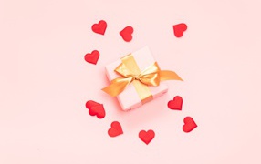 Подарок с бантом на розовом фоне с красными сердечками