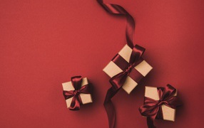 Три подарочные коробки с бантами на красном фоне