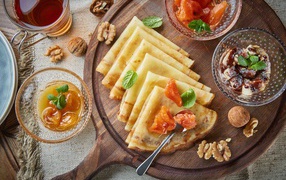 Тонкие блины с орехами и джемом на столе на Масленицу