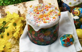 Кулич с глазурью на столе с цветами и яйцами на Пасху