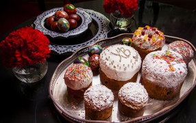 Много куличей на столе с гвоздиками и крашеными яйцами на праздник Пасха