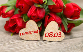 Два сердечка на столе с букетом красных тюльпанов на 8 марта 