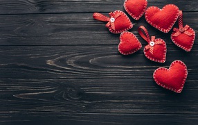 Много красных сердечек из фетра на деревянном столе