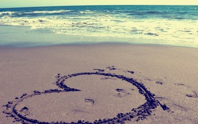 Большое сердце на мокром песке на пляже