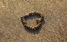 Сердце из мелкий морских камей на песке 