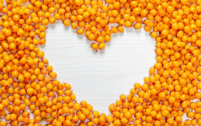 Сердце из ягод облепихи на столе 