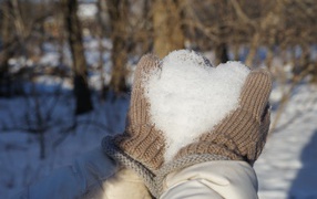 Снег в руках у девушки в перчатках 
