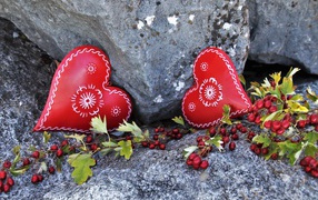 Два сердца лежат у камня с красными ягодами
