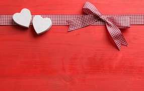 Два сердечка с бантом на красном фоне