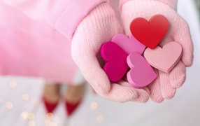 Деревянные сердечки в руках девушки в розовых перчатках 