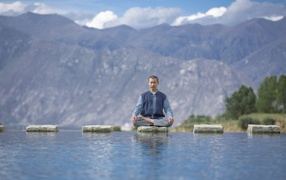 Мужчина азиат в позе лотоса медитирует у воды 