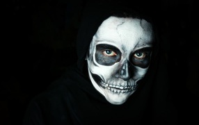 Мужчина в черном наряде с гримом на лице на Хэллоуин