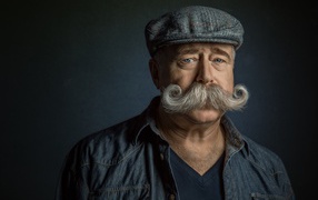 Мужчина в кепке с большими усами на лице 