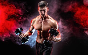 Мускулистый мужчина с гантелями в руках на черном фоне с дымом