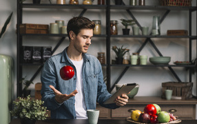 Young man with a tablet and an apple in his hand