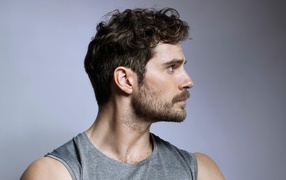 Красивый мужчина, актер Генри Кавилл на сером фоне