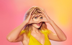 Красивая певица Тейлор Свифт делает сердце из рук на лице