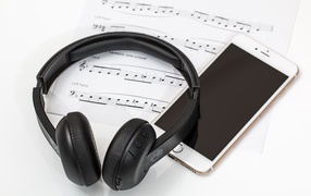 Наушники на столе с нотами и смартфоном